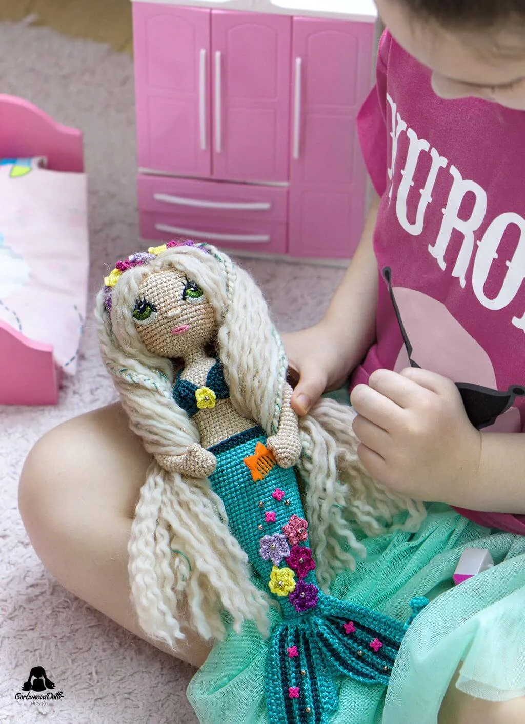 Child playing happily with a beautifully crocheted seamless amigurumi mermaid doll created using the Mermaid crochet pattern