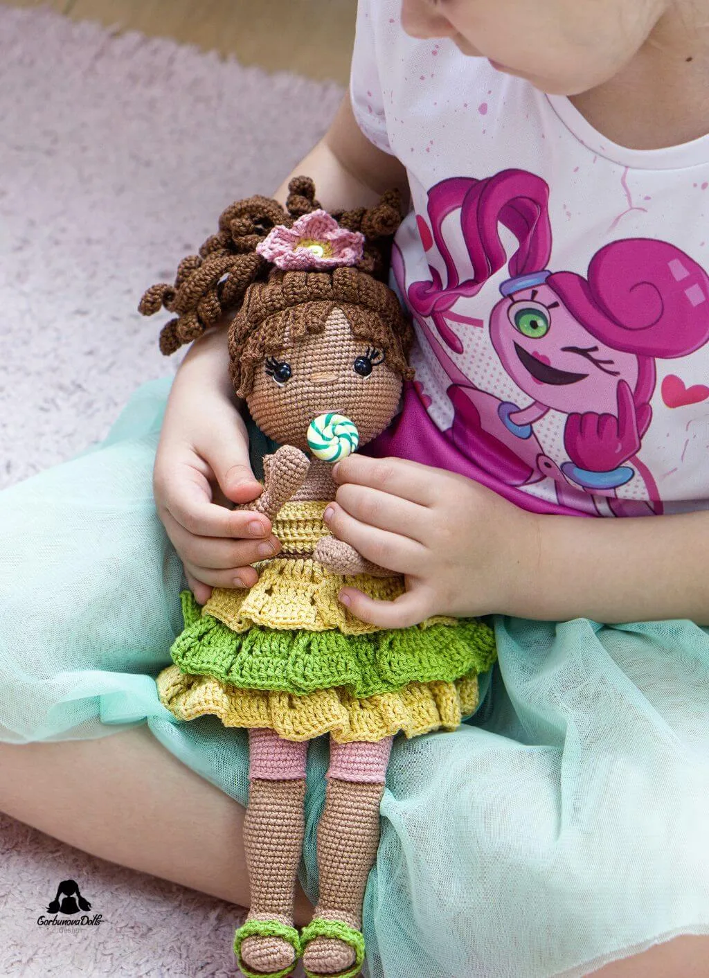 Little girl joyfully playing with Emily, a crochet doll made from an amigurumi doll pattern