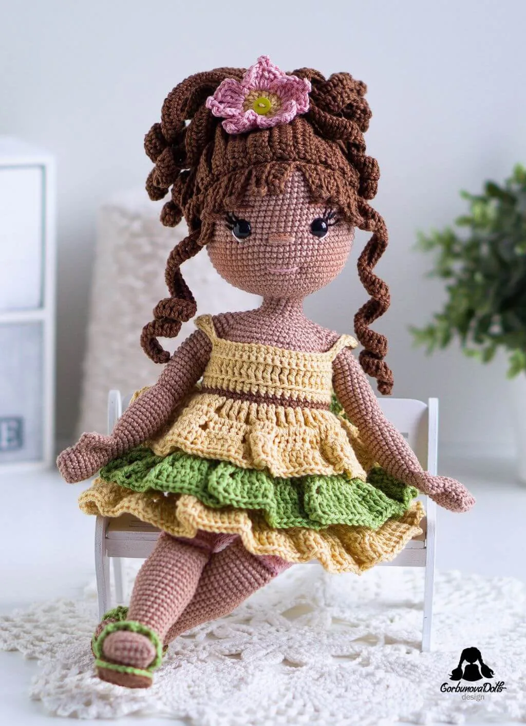 Emily amigurumi doll sitting on a bench wearing removable crochet clothes