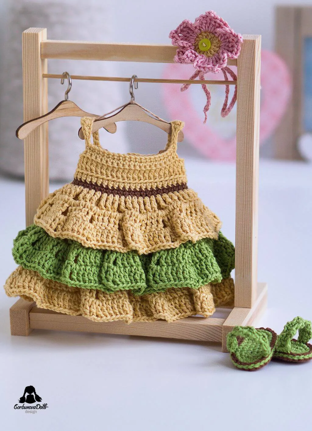 Crocheted dress for Emily hanging on a miniature rack – part of the amigurumi doll pattern
