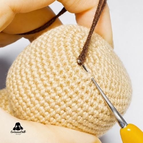 crochet doll hair tutorial – hook inserted into the head to catch a folded yarn strand
